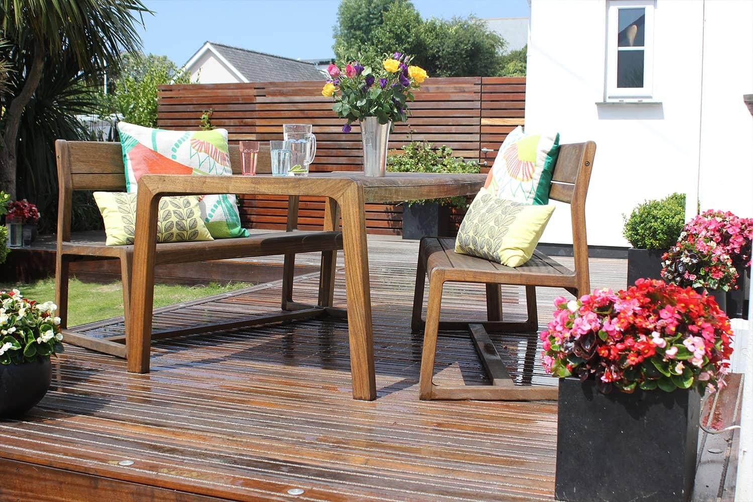 Timber garden furniture with colourful furnishings on non-slip hardwood deck in summer